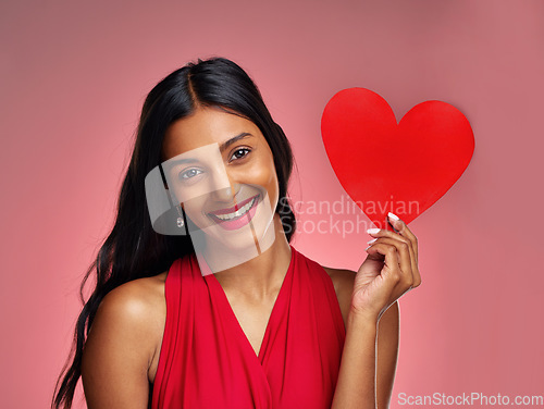 Image of Portrait, heart and smile with a woman on a pink background in studio for love or romance. Valentines day, emoji and social media with a happy young female holding a shape or symbol of affection