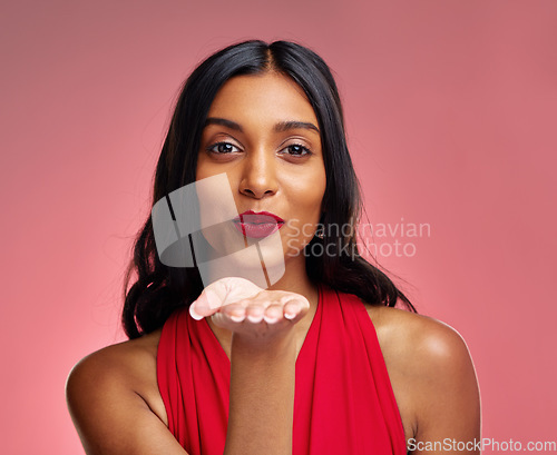 Image of Woman, red lipstick and beauty, blow kiss with makeup and flirt, cosmetics and glow on pink background. Cosmetology, Indian female model pout with color in portrait and shine with wellness in studio