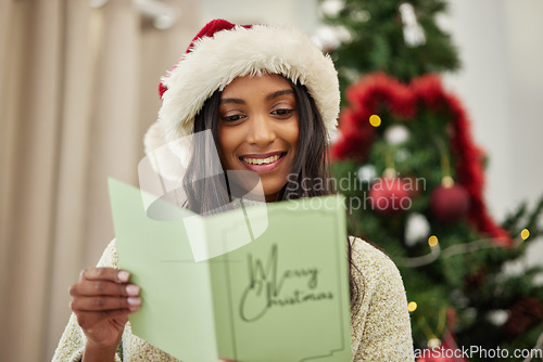 Image of Happy girl reading Christmas card, letter or note in home living room in winter holiday celebration. Smile, festive or Indian woman with emotional xmas greeting message, wishes or kind gift in house