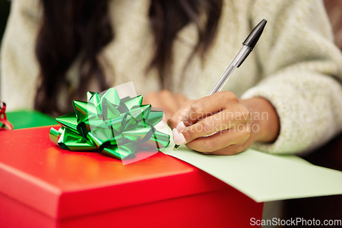 Image of Woman, hands and writing on Christmas gift, note or letter in surprise, festive season or December holiday. Hand of female person with pen and paper on present or box with ribbon for package in house