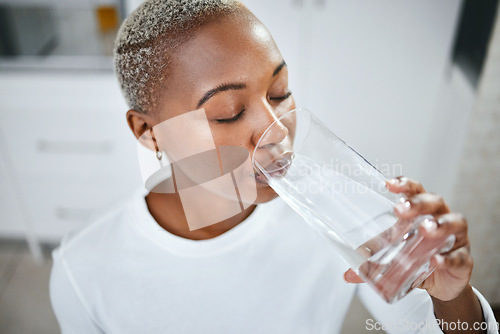 Image of Health, glass and woman drinking water for hydration, wellness and liquid nutrition at her home. Thirsty, energy and African female person enjoying cold healthy drink in the kitchen of her apartment.