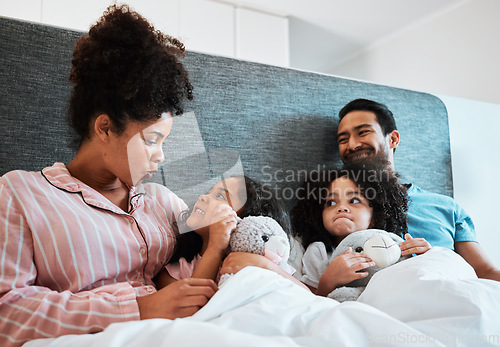 Image of Love, conversation and kids laying with their parents in their bedroom talking, relaxing and bonding. Happy, smile and girl children speaking and resting with their mother and father at their home.