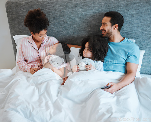 Image of Bonding, discussion and children in the bed with their parents talking and relaxing together in the room. Happy, smile and girl kids speaking for conversation with their mother and father in bedroom.