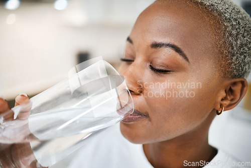 Image of Wellness, glass and woman drinking water for health, hydration and liquid nutrition at her home. Thirsty, energy and African female person enjoying cold healthy drink in the kitchen of her apartment.