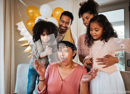 Image of Birthday, surprise and children with excited grandmother at party for event, celebration and social gathering. Happy family, celebrate and shocked grandma with parents and kids for presents at home