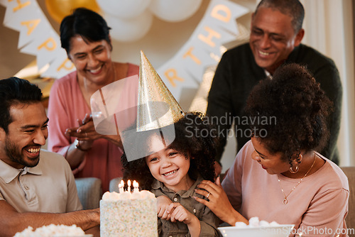 Image of Birthday, happy and parents with cake for child in living room for party, celebration and social event. Family, surprise and excited kid with dessert, snacks and sweet treats with candles at home