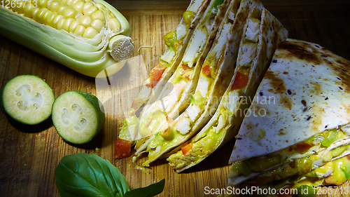 Image of Mexican quesadilla with chicken, cheese and peppers on wooden table