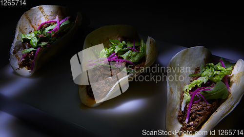 Image of Three pork carnitas street tacos in yellow corn tortilla.