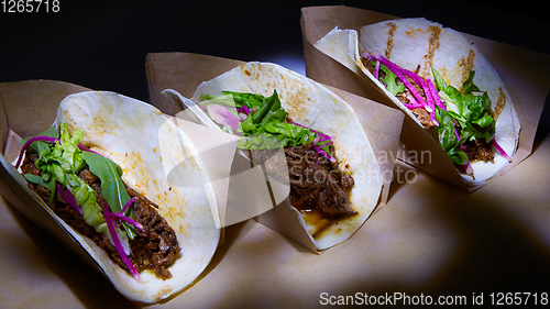 Image of Three pork carnitas street tacos in yellow corn tortilla.