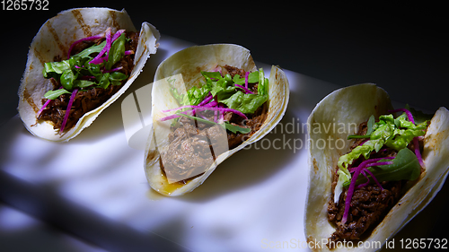 Image of Three pork carnitas street tacos in yellow corn tortilla.