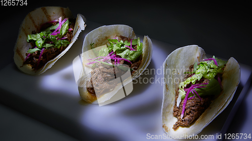 Image of Three pork carnitas street tacos in yellow corn tortilla.