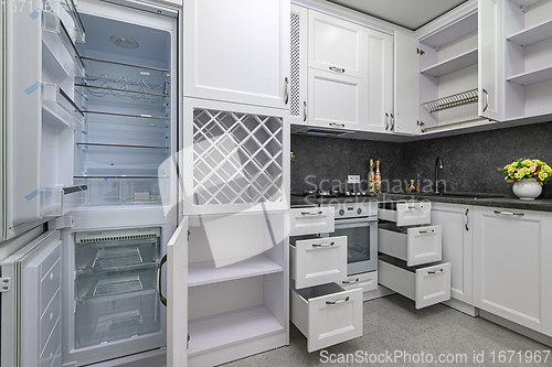 Image of Open doors and drawers open at modern white kitchen