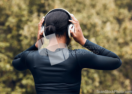 Image of Fitness, back view of woman in woods and with headphones listening to music for workout. Exercise or committed, training or focused and female athlete listen to podcast for motivation in nature