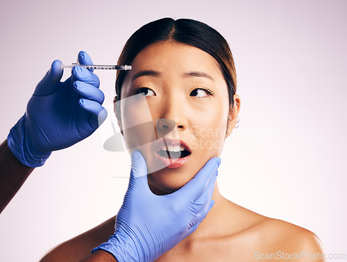 Image of Woman, needle and fear on face in studio for surgery, cosmetics and shock with collagen by white background. Japanese patient, doctor and syringe for dermatology, change and pain for skin aesthetic