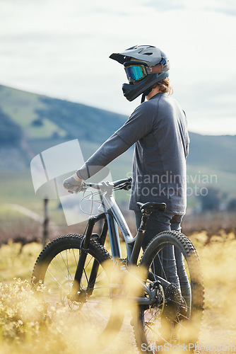 Image of Sports, cycling and man with helmet on bicycle in nature for training, workout and exercise in countryside. Fitness, cyclist and person with mountain bike for adventure, freedom and ride on dirt road