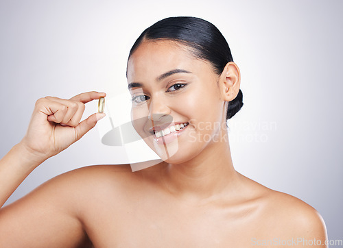 Image of Woman, beauty and pill in studio portrait for skincare, health or smile for glow, essential oil and white background. Girl, model or happy for supplement, beauty drugs or pharma product for self care