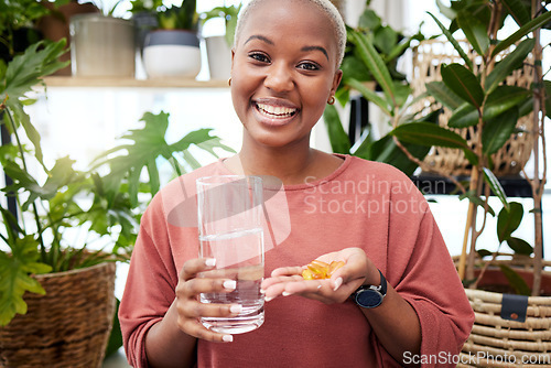 Image of Portrait, water and medicine with a black woman in her home holding vitamins or supplements for health. Smile, glass and pills with a happy young female person drinking for wellness or hydration