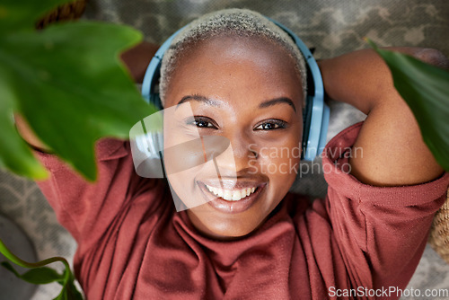 Image of Woman, portrait and headphones for listening to music to relax with plants for peace and calm. Face of a happy black female person streaming sound, audio and podcast or radio online at home
