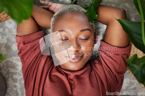 Image of Relax, plants and above of black woman in home for wellness, zen mindset and calm energy. Nature, happy and face of female person laying on floor with eco friendly ferns, leaves and house plant