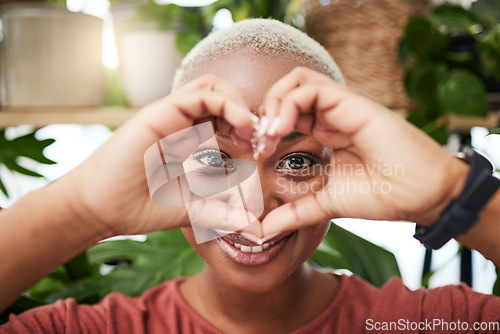 Image of Black woman, portrait and face with heart hands for love, sign or shape in natural wellness or eco friendly store. Happy African female person with loving emoji, symbol or gesture for care in garden