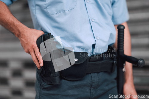 Image of Hand, gun and security with an officer on duty or patrol in the city for safety and law enforcement. Police, service and armed response with a guard outdoor in an urban town for crime prevention