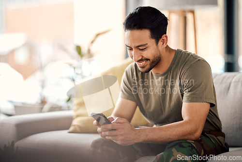 Image of Happy, man and texting on cellphone in living room for online mobile app, scroll social media and notification on sofa. Asian male person typing on smartphone, contact and internet download at home