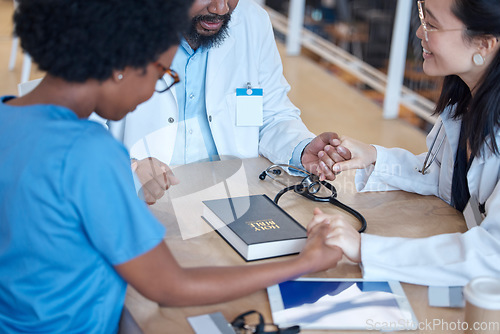 Image of Hands, bible and a medical team praying during a meeting in a hospital office together. Medical, trust or teamwork with doctors and nurses asking God or Jesus for miracle help in a health clinic