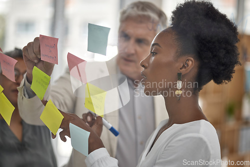 Image of Meeting, planning and glass with a black woman leading a presentation in a boardroom for company strategy. Teamwork, presentation and sticky notes in an office with a female employee talking to staff