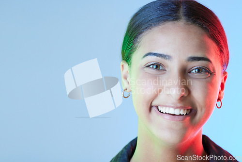 Image of Portrait, smile and mockup with a woman on a blue background in studio for a logo or branding. Happy, space for marketing or advertising and neon lighting on the face of a female brand ambassador