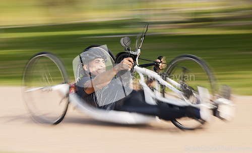 Image of Cycling, fitness and man with disability, speed and training for competition and exercise on bike. Motion blur, workout and person on fast recumbent bicycle on outdoor race track for challenge