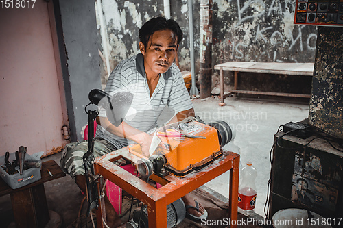 Image of Man with grinder machine working on the street, Indonesia