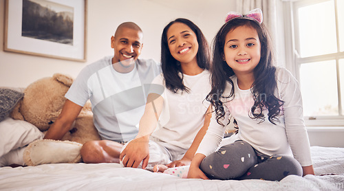 Image of Family, relax and happy portrait on a bed at home with a smile and comfort for quality time. Man, woman or parents and a latino girl kid together in the bedroom for morning bonding with love and care