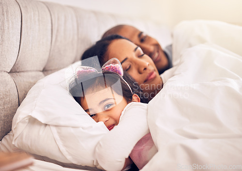 Image of Family, portrait of a girl in bed with her parents and morning with adorable little child in the bedroom at home. Face, smile or happy with a young female kid in the house to relax with mom and dad