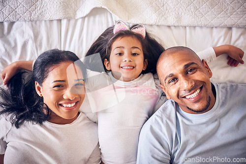 Image of Mother, father and portrait of a child on a bed in a family home with a smile and comfort for quality time. Above a man, woman and a girl kid together in the bedroom for morning bonding with love