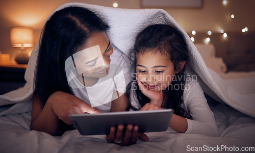 Image of Mother, child and tablet with blanket at night in home for online games, reading ebook story and movies. Happy mom, girl kid and streaming cartoon on digital technology, media connection and bedroom