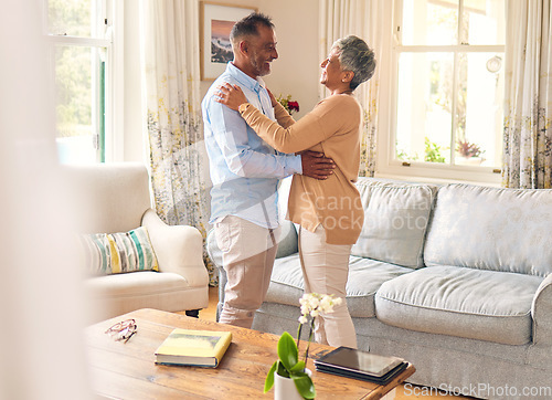 Image of Love, romance and dance with a senior couple in the living room of their home together for bonding. Marriage, retirement or bonding with an elderly man and woman dancing in the lounge of their house