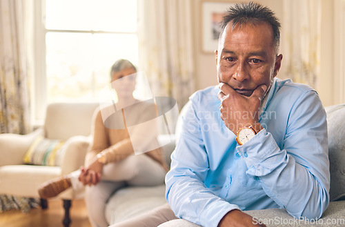 Image of Couple fighting, stress and divorce with a senior man on a sofa in the living room of his home after an argument. Sad, anxiety or depression with an elderly male pensioner looking down after conflict