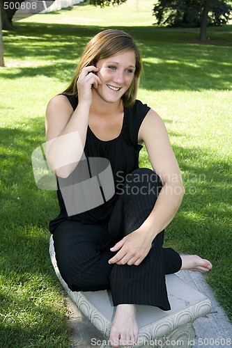 Image of Beautiful Girl in the Park in a Black Dress Talking on the Phone