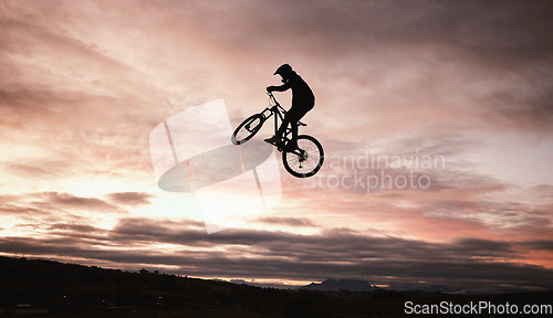 Image of Sunset, dirt bike and jump with action in outdoor with sport in nature for adventure or risk. Motorcycle, silhouette and freedom with training or sky with speed in desert with person driving.