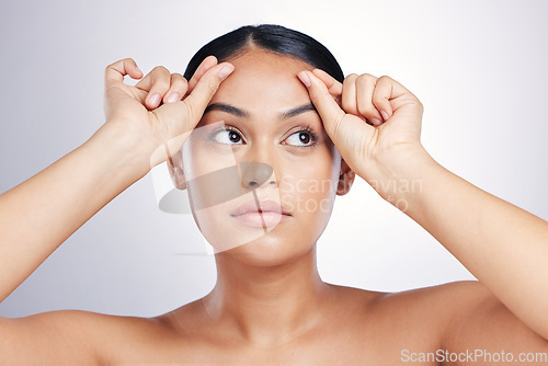 Image of Face, beauty and eyebrows with a model woman in studio on a gray background for skincare or cosmetics. Facial, makeup and eyes with a young female person touching her skin after facelift treatment