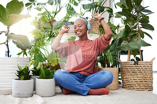 Image of Music, dance and radio with a black woman in her home by plants while streaming an audio playlist. Freedom, headphones and subscription service with a carefree young female person in her house