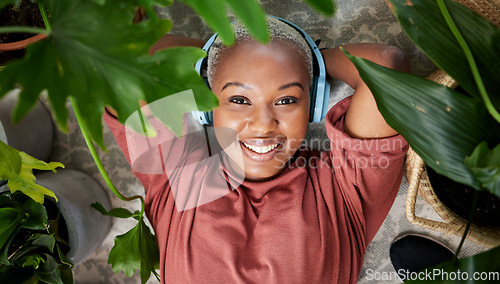 Image of Headphones, portrait and woman listening to music to relax with plants for peace and calm. Face of a happy black female person streaming sound, audio and podcast or radio online with a smile at home