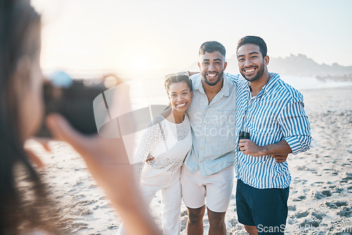 Image of Happy, photo and friends at the beach with a photographer for summer memory, holiday or bonding. Smile, camera and a woman taking a picture of a group of people at the ocean during a vacation