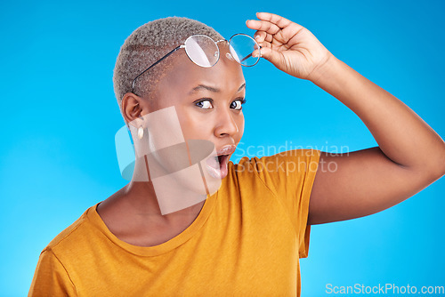 Image of Portrait, news and black woman shocked, gossip and announcement against a blue studio background. Face, female person and model with glasses, surprise and deal with omg facial and wow with expression