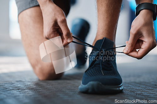 Image of Fitness, shoes and tie with a sports man in the gym getting ready for a cardio or endurance workout. Exercise, running and preparation with laces of a male athlete or runner at the start of training