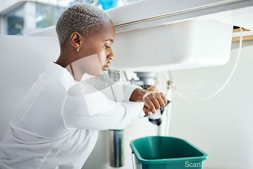 Image of Plumbing, leak and time with a black woman in the bathroom of her home waiting for repair assistance. Sink, emergency and watch with a young female homeowner in her house to stop water using a bucket