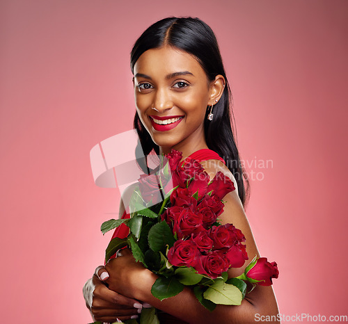 Image of Pageant, flowers and portrait of an Indian woman on a studio background for valentines day. Smile, happy and a young model or girl with a floral bouquet on a red backdrop for luxury present of roses