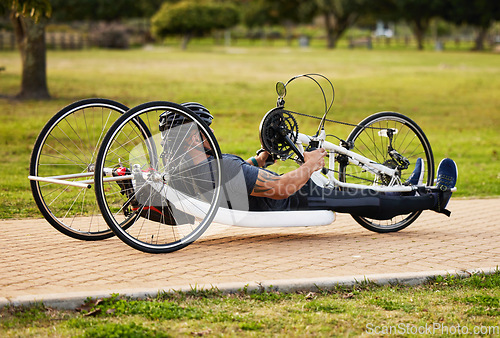 Image of Health, cycling and fitness with man and handcycle on road for training, sports and challenge. Exercise, workout and marathon with person with a disability in park for cardio and wellness