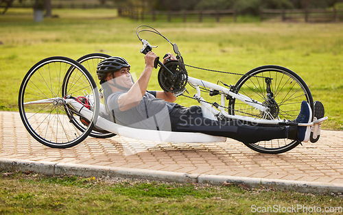 Image of Cycling, sports and fitness with man and handcycle on road for training, bike and challenge. Exercise, workout and marathon with person with a disability riding in park for cardio and health