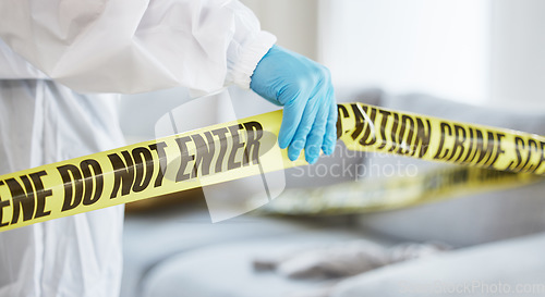 Image of Forensics, crime scene and tape with investigator hand in house lounge for investigation, research or safety. Medical, science and evidence with closeup of person for examination, police and security